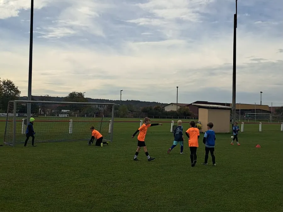 Kinder in orangen Trikots beim Torschusstraining auf dem Rasenplatz