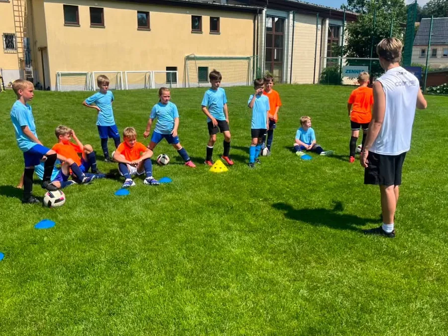 Trainer erklärt einer Gruppe Kinder die nächste Übung